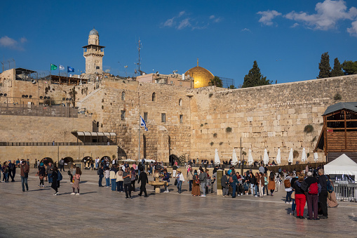 Jerusalem, Israel - November 22, 2023: People at the Western Wall with the Dome of the Rock in the background, a sunny day in Jerusalem.