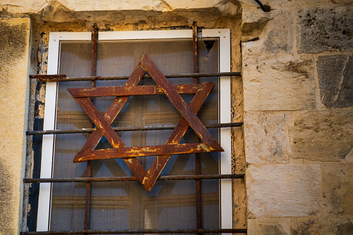 Rustic Star of David on window grille in Jerusalem's historic quarter, symbolizing Jewish heritage and culture.