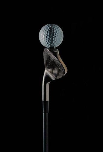 photo of a golf stick with the focus set on the golf ball on the stick and with a dark background