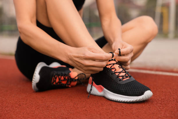 istock Woman tying shoelaces before training outdoors, closeup 1954424275