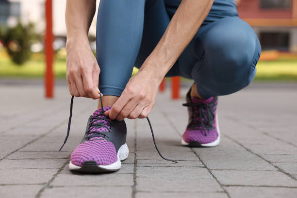 istock Woman tying shoelaces before training outdoors, closeup 1954425374