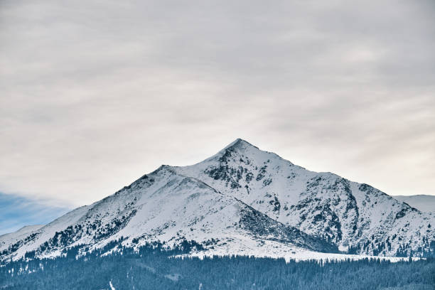 Winter mountain view with cloudy sky and snowcapped peaks