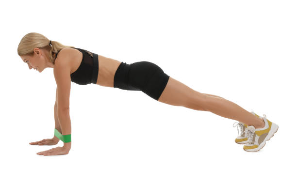 Woman exercising with elastic resistance band on white background