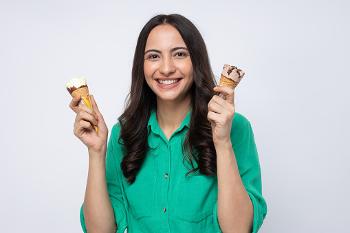Attractive young woman eating ice cream standing isolated over white background