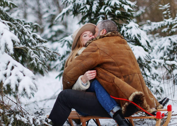 istock couple in love having fun spending winter time, sitting and hugging on sled 1954447569