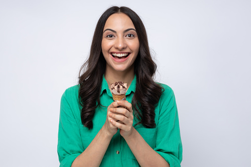 Attractive young woman eating ice cream standing isolated over white background