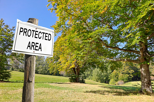 Protected area written on a sign against a woodland - Sign indicating concept