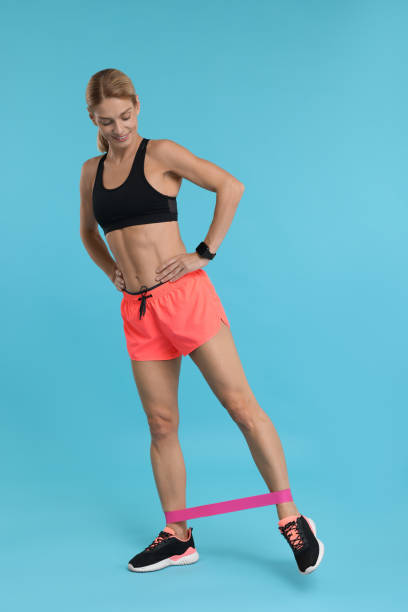 istock Woman exercising with elastic resistance band on light blue background 1954456844