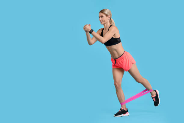 istock Woman exercising with elastic resistance band on light blue background. Space for text 1954457387