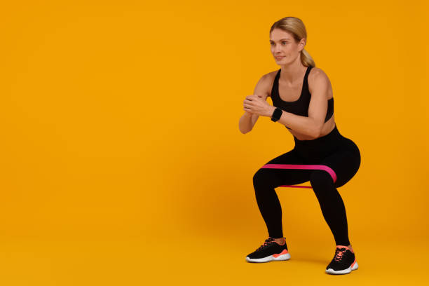 istock Woman exercising with elastic resistance band on orange background. Space for text 1954458498