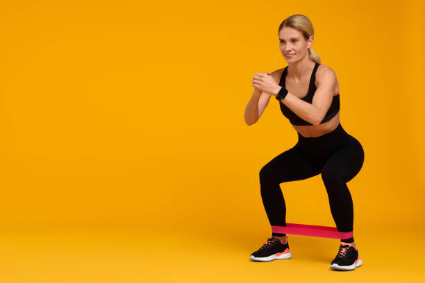 istock Woman exercising with elastic resistance band on orange background. Space for text 1954458507