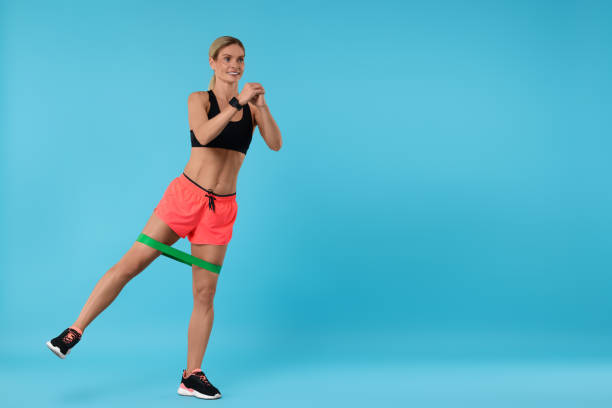 istock Woman exercising with elastic resistance band on light blue background. Space for text 1954458538