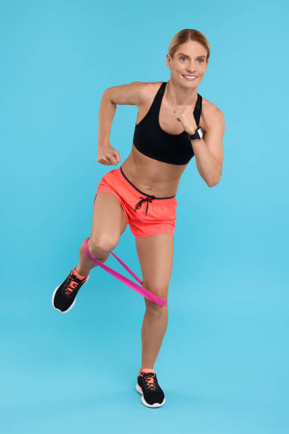 istock Woman exercising with elastic resistance band on light blue background 1954459685