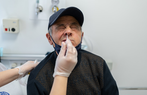 Nurse Performing A Nasal Swab Test On Senior Patient In Hospital