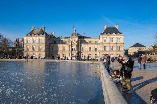 Paris, France, 20th of January 2024, Icy lake and  Palais du Luxembourg in  Jardin du Luxembourg (Luxembourg garden) of Paris,