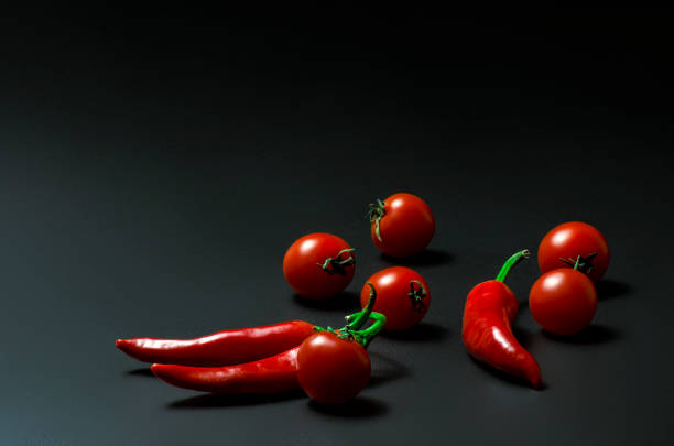 cherry tomatoes and chili peppers on a black background