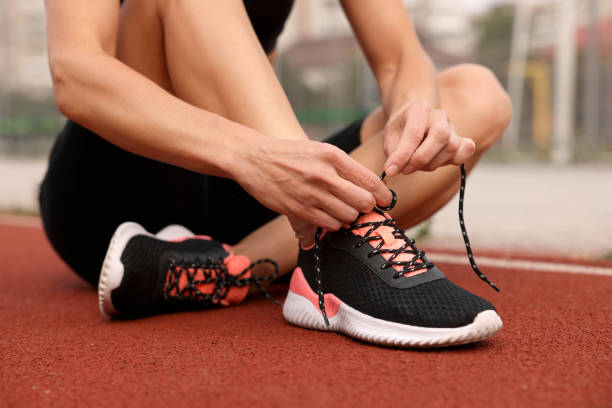 istock Woman tying shoelaces before training outdoors, closeup 1954514824