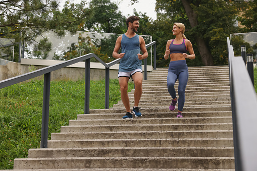 Healthy lifestyle. Happy couple running down stairs outdoors