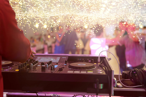 Mixing console is played by DJ and couples dancing on the dance floor in the background and empty space for text