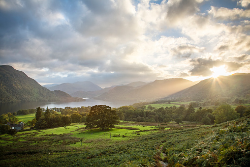 Ullswater landscape with sun rays at sunset in autumn. Lake District, Cumbria, UK