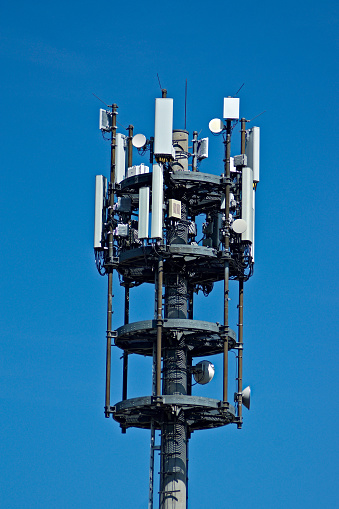 A modern cell phone mast in Germany. Many antennas in front of a blue sky.