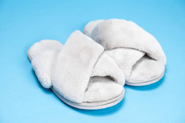 istock Modern stylish fluffy grey slippers on blue background 1954540864