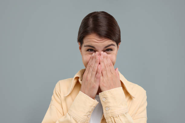 istock Embarrassed woman covering mouth with hands on grey background 1954540875