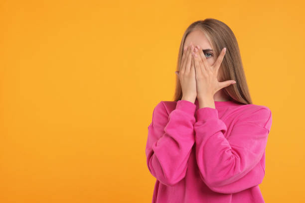 istock Embarrassed woman covering face with hands on orange background, space for text 1954544040