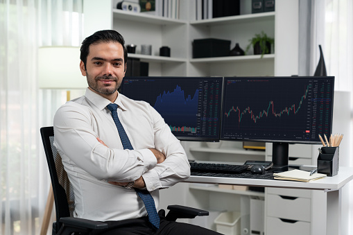 Profile of successful in trader businessman looking at camera with two stock exchange investment screens with good-looking pose in dynamic financial technology graph stock market at office. Surmise.