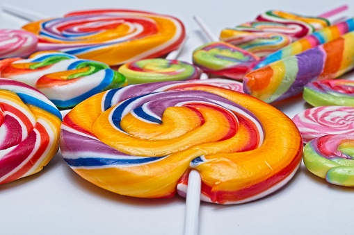 Close up side view of multicoloured candies on white background with selective focus