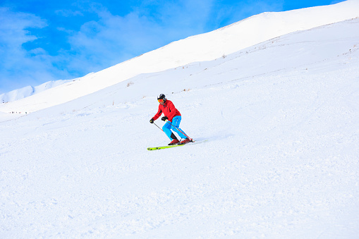 Winter sport. Vital active senior men snow skier skiing, enjoying on sunny ski resorts. Skiing carving at high speed against blue sky. Alps  ski area. Ski resort Dolomiti superski, Sellaronda,  italy, Europe.