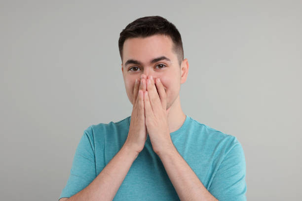 istock Embarrassed man covering mouth with hands on grey background 1954590301