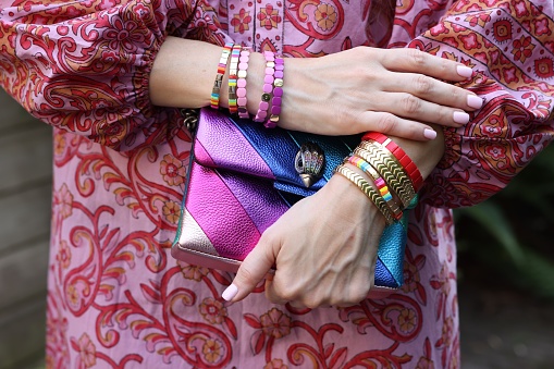 Woman with stylish purse wearing bracelets outdoors, closeup