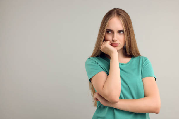 Resentful woman on grey background, space for text