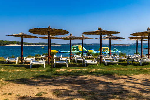 Deckchairs for rent and straw umbrellas on the beach Croatia Pula Kamenjak