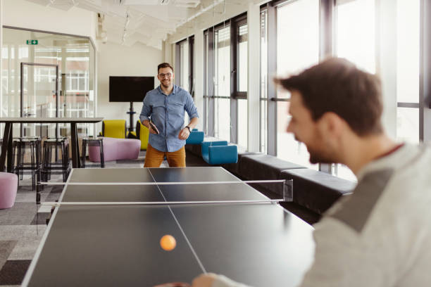 Colleagues Playing Ping Pong Table Tennis at Office Break Out Area