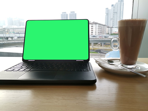 A glass of hot chocolate drink next to laptop in cafe