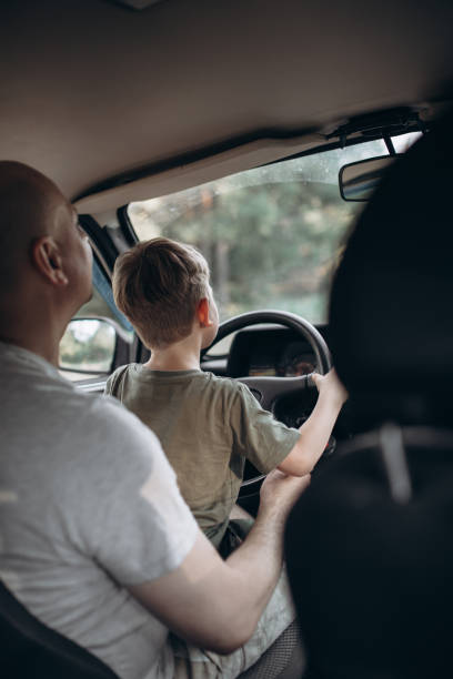 istock Dad teaches his son to drive a car view from the back 1954641857