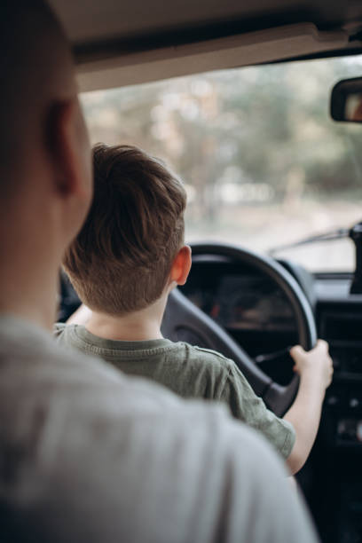 istock Dad teaches his son to drive a car view from the back 1954641900