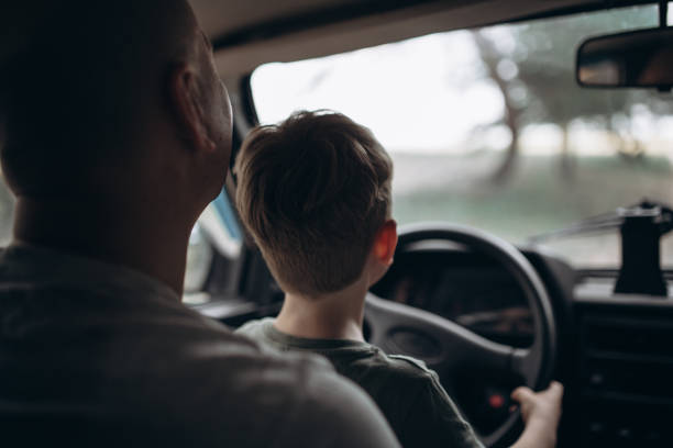 istock Dad teaches his son to drive a car view from the back 1954641911