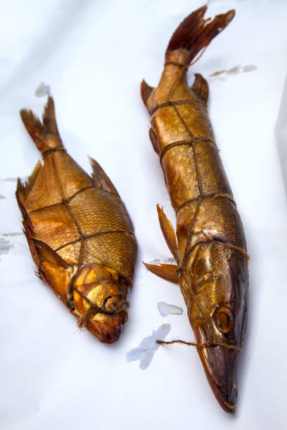 istock Smoked freshwater pike and common bream fish for home use on white paper. 1954643554