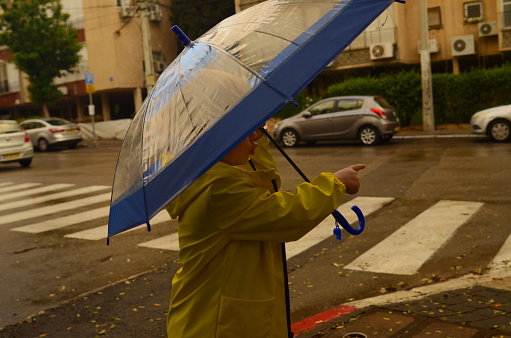 Little cute boy rejoices in the rain, holding an umbrella.