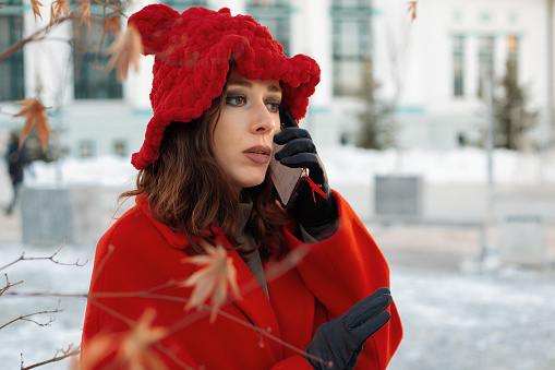 Close-up of a young woman on winter snowy background talking on the phone