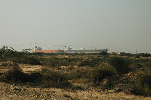 The tank ships on the distant horizon line against the backdrop of a junkyard in Pakistan