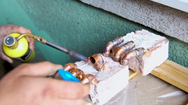 Soldering and sweating copper elbow coupling tubing with propane torch stock video