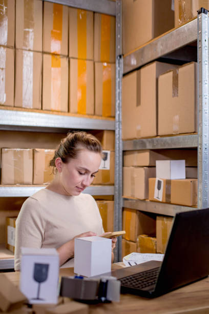 istock Young entrepreneur small business checking internet orders on smartphone and preparing boxed items for delivery to customers 1954672814
