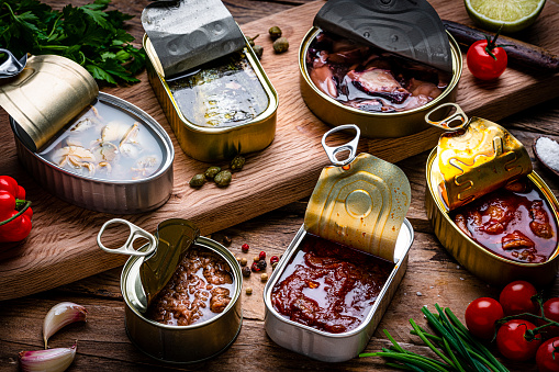 Composition of canned fish and seafood shot on rustic wooden table. High resolution 42Mp studio digital capture taken with Sony A7rII and Sony FE 90mm f2.8 macro G OSS lens