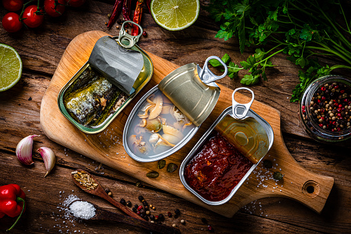 Overhead view of three open seafood cans shot on rustic wooden table. High resolution 42Mp studio digital capture taken with Sony A7rII and Sony FE 90mm f2.8 macro G OSS lens