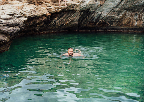 Young man swimming in natural pool Giola on Thassos island, Greece