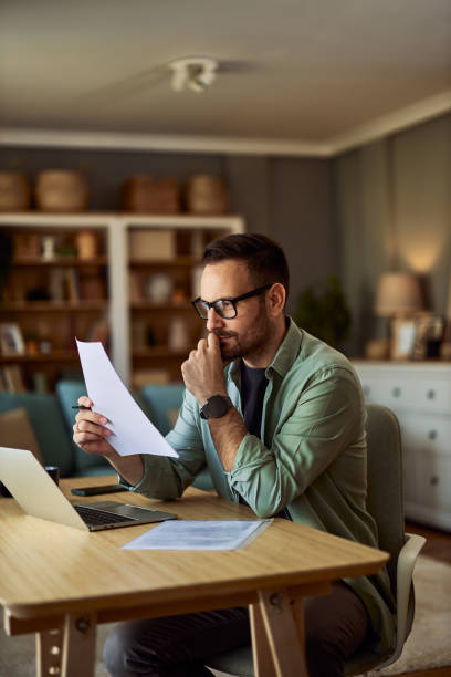 istock A focused male data researcher analyzing a document while sitting in front of a laptop. 1954701073